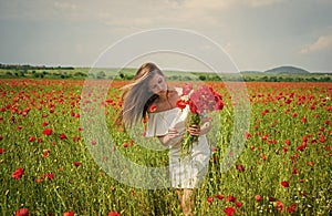 beautiful woman gather red poppy flower bouquet in field. summer or spring nature. seasonal beauty landscape. young girl