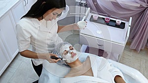 Beautiful woman getting facial mask at beauty salon