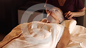 Beautiful woman getting head skin massage in beauty spa salon. Close up portrait woman receiving head and hair massage