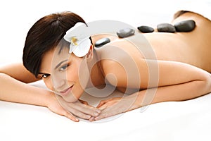 Beautiful Woman Getting Hot Stone Massage in Spa Salon.