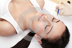 Beautiful woman getting lifting botox injection in forehead. Close-up woman hyaluronic acid injection. injections of skin rejuvena