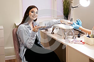 Beautiful woman getting manicure in a salon and holds a white cup of coffee