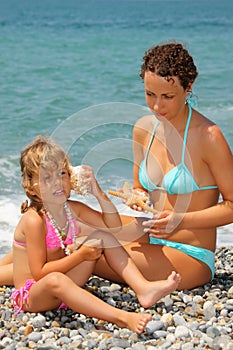 Beautiful woman with girl has leant seashell bowl