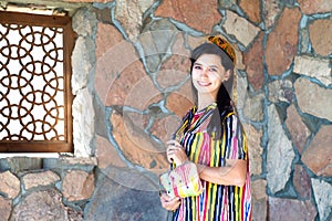 Beautiful woman, girl in national folk Uzbekistan dress against stone wall and ancient window background