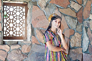 Beautiful woman, girl in national folk Uzbekistan dress against stone wall and ancient window background