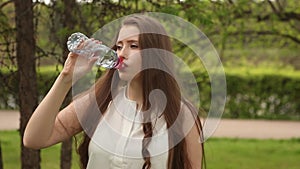 Beautiful woman or girl quenches thirst on a hot sunny day.