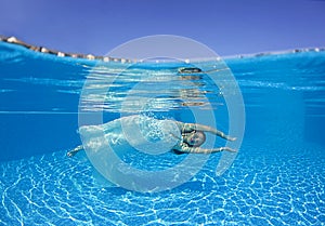 Beautiful woman girl white dress underwater diving swim blue sunny day pool