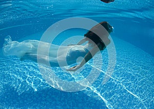 Beautiful woman girl white dress underwater diving swim blue sunny day pool