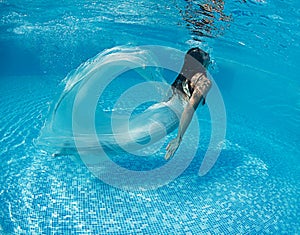 Beautiful woman girl white dress underwater diving swim blue sunny day pool