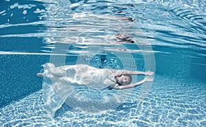 Beautiful woman girl white dress underwater diving swim blue sunny day pool