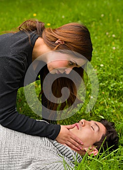 Beautiful woman giving first aid to a handsome young man, cardiopulmonary resuscitation, in a grass background