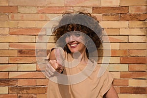 beautiful woman giving the thumbs up. The woman has a brick wall in the background. Concept all goes well