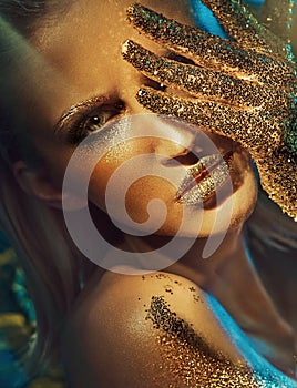 Beautiful woman with glittering golden hands and lips