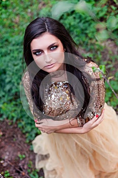 Beautiful woman in gold dress is smiling and hugging herself