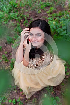 Beautiful woman in gold dress is smiling and hugging herself