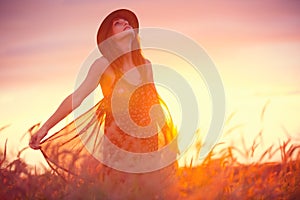 Beautiful woman in golden field at sunset