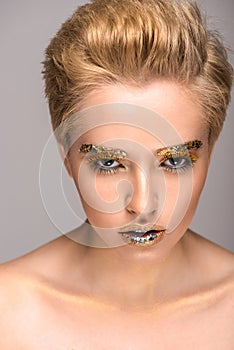 beautiful woman with golden glitter on face looking at camera