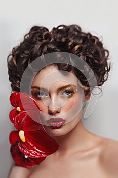 Beautiful woman with golden makeup and red flowers