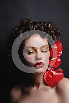 Beautiful woman with golden makeup and red flowers