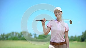 Beautiful woman golf player with club smiling on camera, favorite hobby, lessons