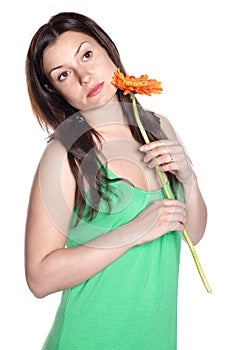 Beautiful woman in green dress holding gerbera flower in hands