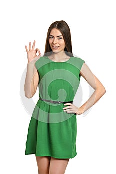 Beautiful woman in green dress showing ok sign on white background