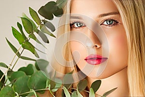 Beautiful woman and green leaves branch, blonde hair, red lipstick make-up face portrait, natural beauty and cosmetics