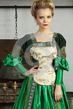 Beautiful woman in green medieval costume stands photo