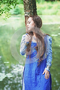 Beautiful woman in green medieval dress near river