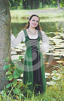 Beautiful woman in green medieval dress near river