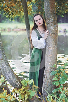 Beautiful woman in green medieval dress near river