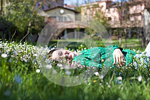 Beautiful woman in green shirt lying down among daisies smiling