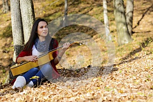 Beautiful woman guitar player girl in the forest