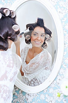 Beautiful woman in hair curlers puts on morning makeup