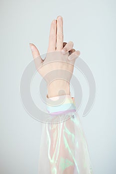 Beautiful woman hands and arms wearing a sweater with holographic effect, modern avantgarde artificial plastic look