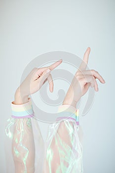 Beautiful woman hands and arms wearing a sweater with holographic effect, modern avantgarde artificial plastic look