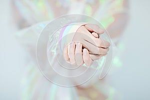 Beautiful woman hands and arms wearing a sweater with holographic effect, modern avantgarde artificial plastic look