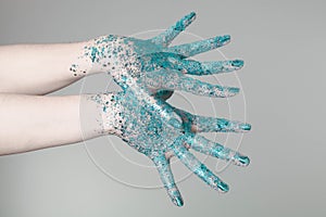 Beautiful woman hands with blue glitter in front of black