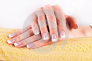 Beautiful woman hands with french nails manicure on yellow towel