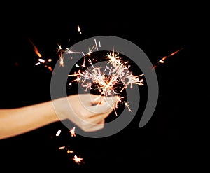 Beautiful woman hands holding sparkler lights in front of black