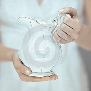 Beautiful woman hands holding vintage antique milk pot