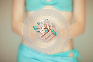 Beautiful woman hands with perfect blue nail polish holding coral necklace, happy bikini beach mood