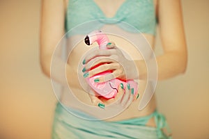 Beautiful woman hands with perfect blue nail polish holding little flamingo, happy bikini beach mood