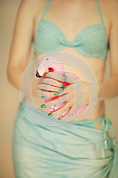 Beautiful woman hands with perfect blue nail polish holding little flamingo, happy bikini beach mood