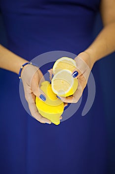 Beautiful woman hands with perfect nail polish holding lemon, yellow fruit on blue