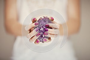 Beautiful woman hands with perfect pink nail polish holding violet amethyst crystal