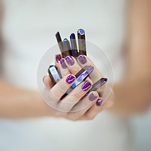 Beautiful woman hands with perfect violet nail polish holding little quartz crystals in purple violet