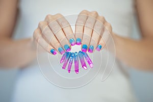 Beautiful woman hands with perfect violet pink and turquoise nail polish