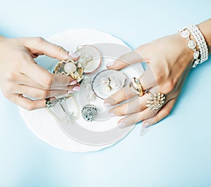 Beautiful woman hands with pink manicure holding plate with pearls and sea shells, luxury jewelry concept