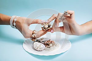 Beautiful woman hands with pink manicure holding plate with pearls and sea shells, luxury jewelry concept